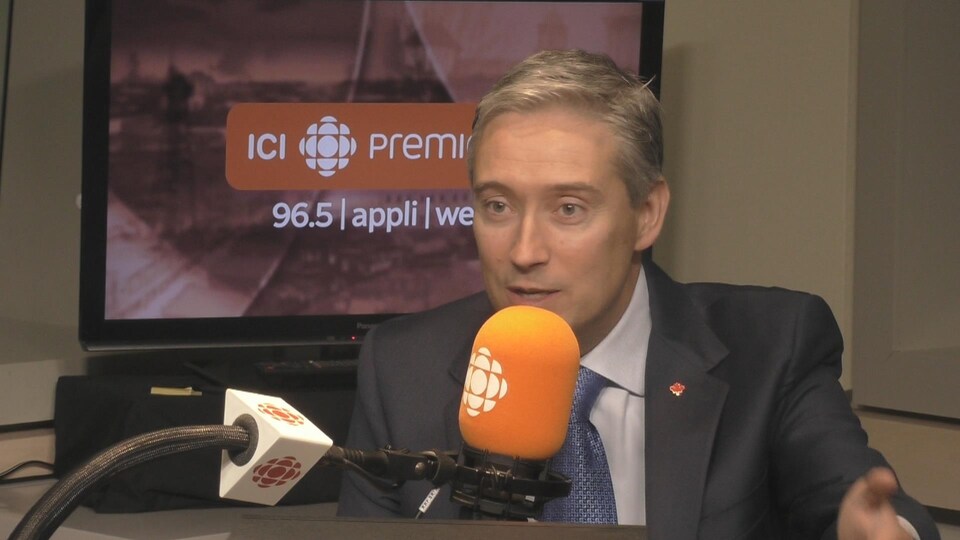 François-Philippe Champagne assis dans le studio radio de Trois-Rivières, avec un micro devant lui.