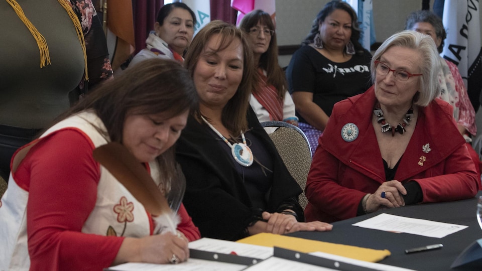 La ministre des Relations Couronne-Autochtones, Carolyn Bennett, l'ex-présidente de l'Association des femmes autochtones du Canada Francyne Joe (milieu) et Viviane Michel, de Femmes autochtones du Québec (gauche), signent une entente à Ottawa.