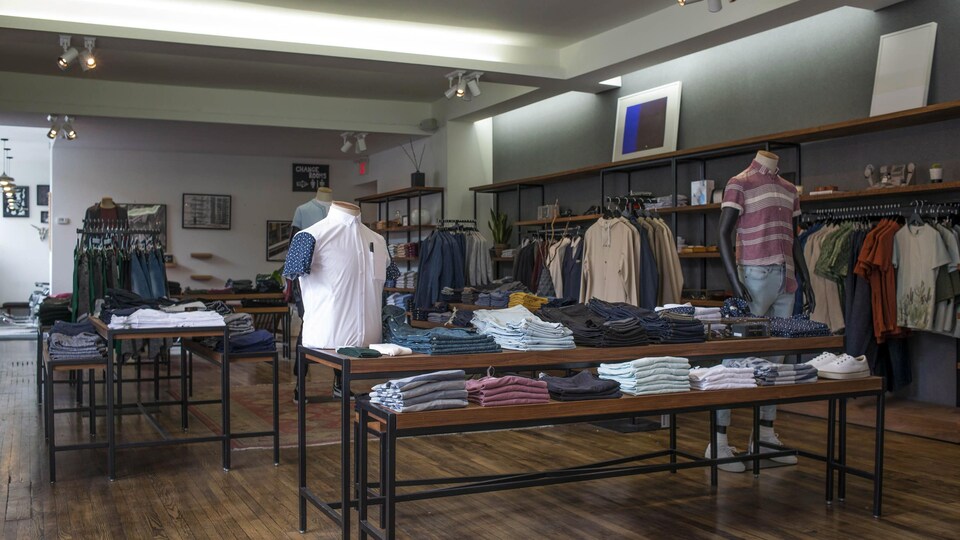 Des chemises et des chandails sont visibles dans un magasin.