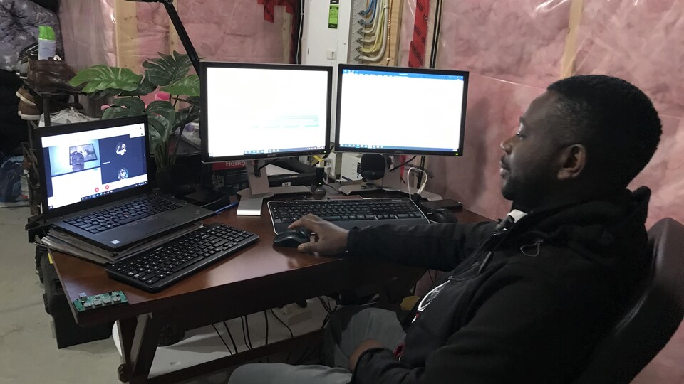 Un homme assis devant des ordinateurs. 