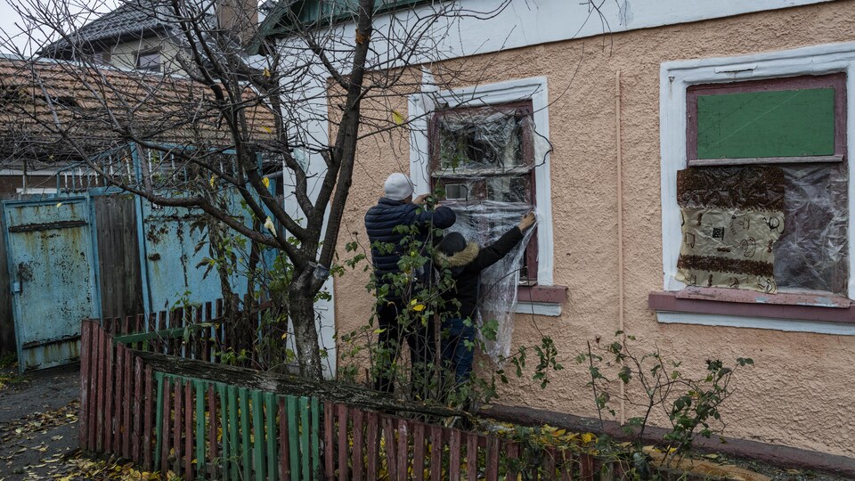 Des habitants de Kherson doublent leurs fenêtres de bâches en plastique.