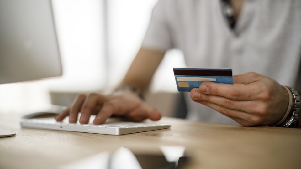 Une personne lit sa carte de crédit devant son ordinateur.