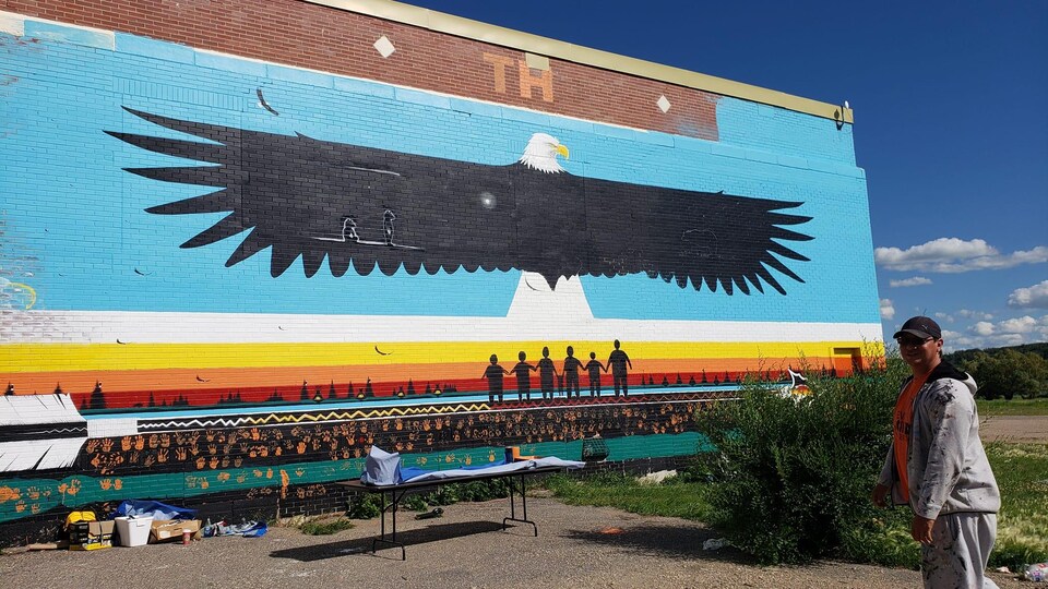 L'artiste Darren Pratt devant l'oeuvre murale pour honorer les enfants disparus des pensionnats à Lebret, en Saskatchewan 
