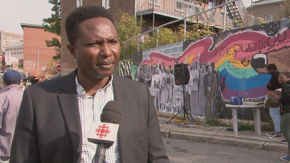 Un homme en entrevue à Radio-Canada, à l'extérieur. Un micro est pointé en direction de son visage.