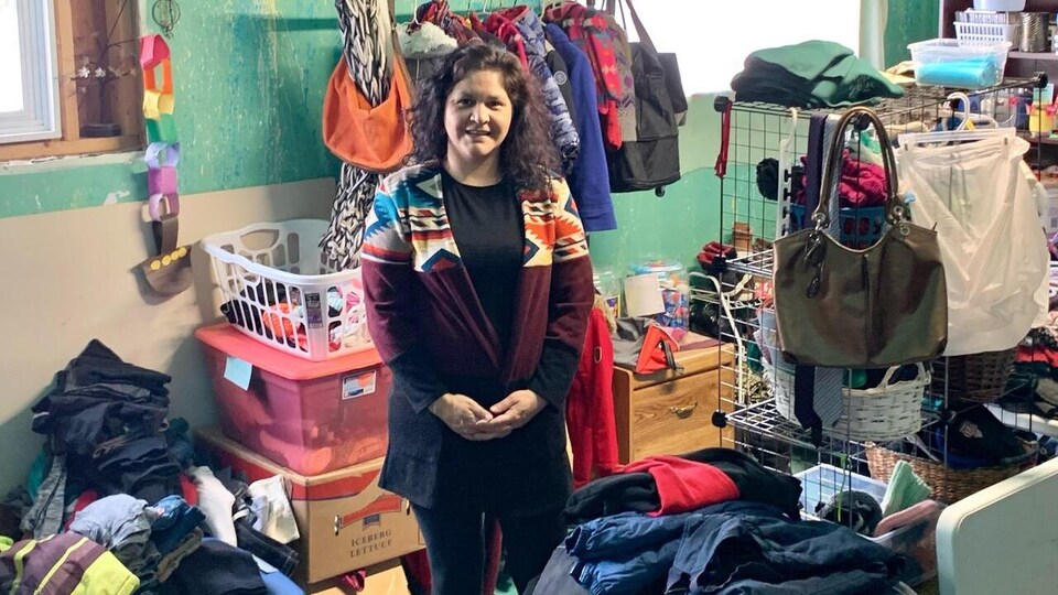 Une femme entourée de vêtements dans une friperie dans son sous-sol.