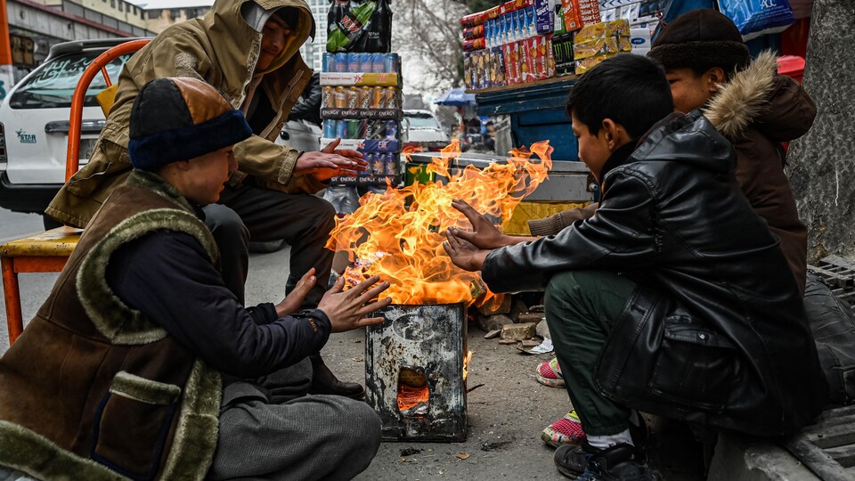 Quatre jeunes Afghans se réchauffent autour d'un feu à Kaboul.