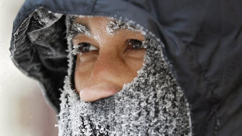 La face d'un homme couverte d'un capuchon et un foulard gelé.