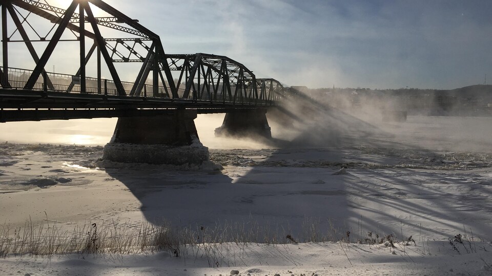 Un pont surplombe une rivière en hiver.