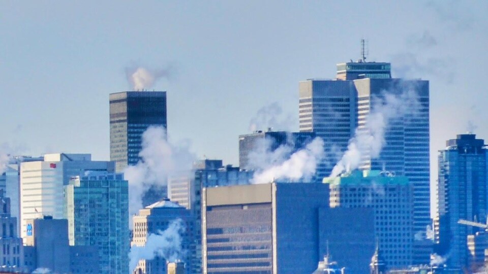 De la fumée blanche au dessus des immeubles du centre-ville de Montréal.