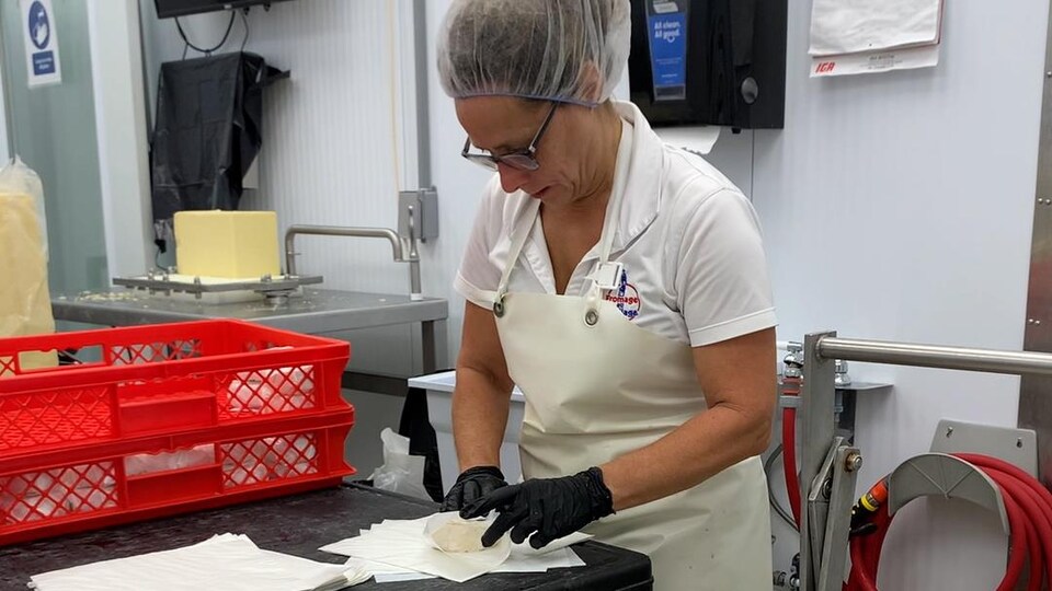 Une femme emballe un fromage.