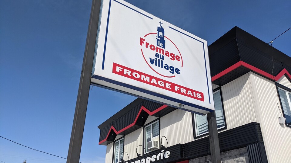 L'affiche de l'entreprise Le Fromage au Village, devant ses locaux, à Lorrainville.