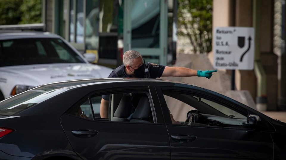 A Canadian customs officer guides a motorist to the border.