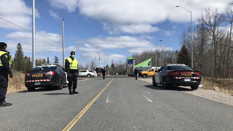 Un barrage avec des voitures de police de chaque bord d'une route et des policiers.