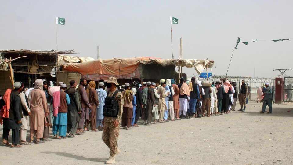 A Pakistani soldier looks at a line of civilians on the Pakistan-Afghanistan border.