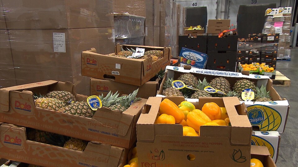 Des caisses remplies de fruits et de légumes sont empilées dans un entrepôt.