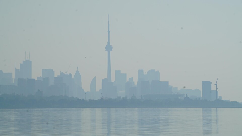 De la fumée obscurcit le ciel de Toronto; la Tour CN et le centre-ville vus du lac Ontario.