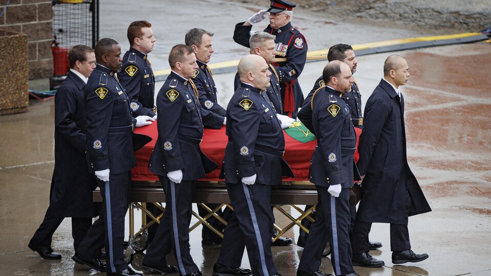 Des agents de police de la PPO en uniforme transportent le cercueil couvert d'un drapeau de l'Ontario.
