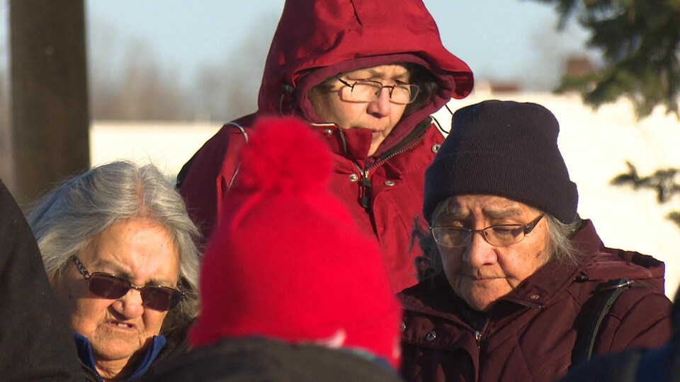 Trois femmes se tiennent près les unes des autres en regardant par terre.