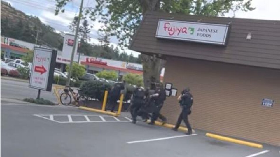 Un groupe de policiers s'élance le long d'un trottoir devant un restaurant.