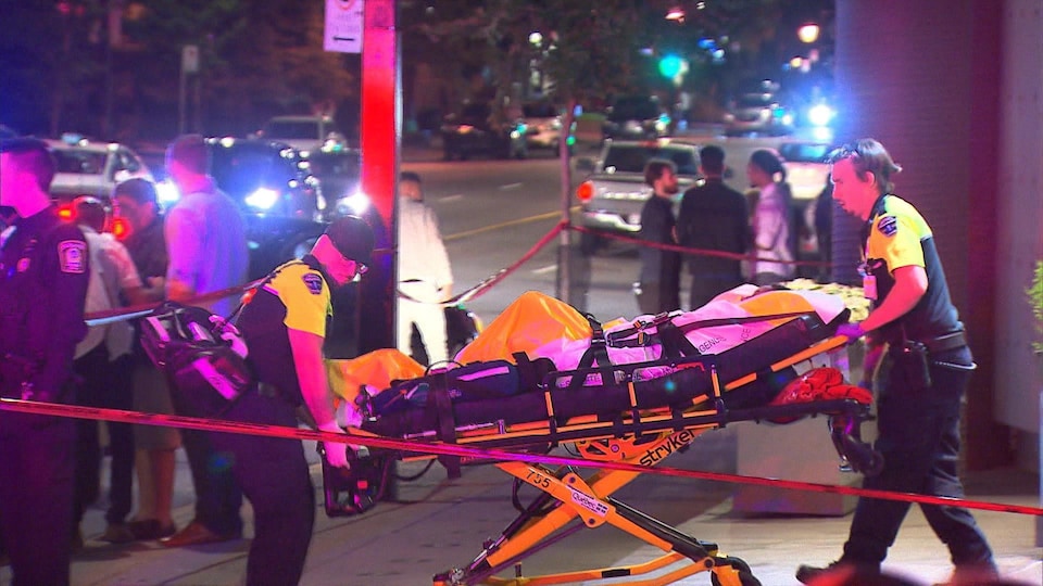 Des ambulanciers transportent une victime atteinte par balle sur une civière.