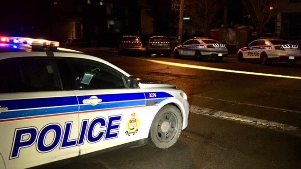 Cinq voitures de la police d'Ottawa à l'intersection d'une rue la nuit.