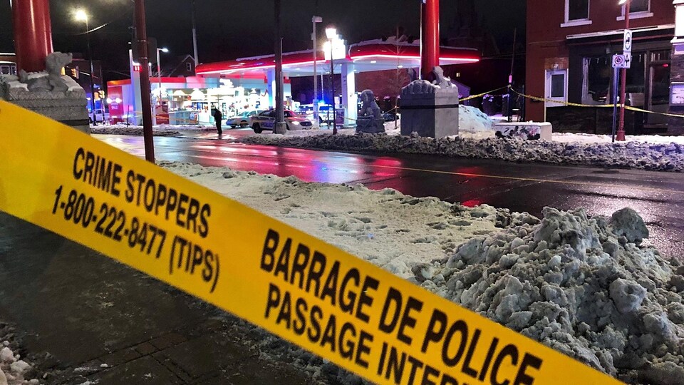 Un ruban de police restreint l'accès à la station-service située à l'intersection.