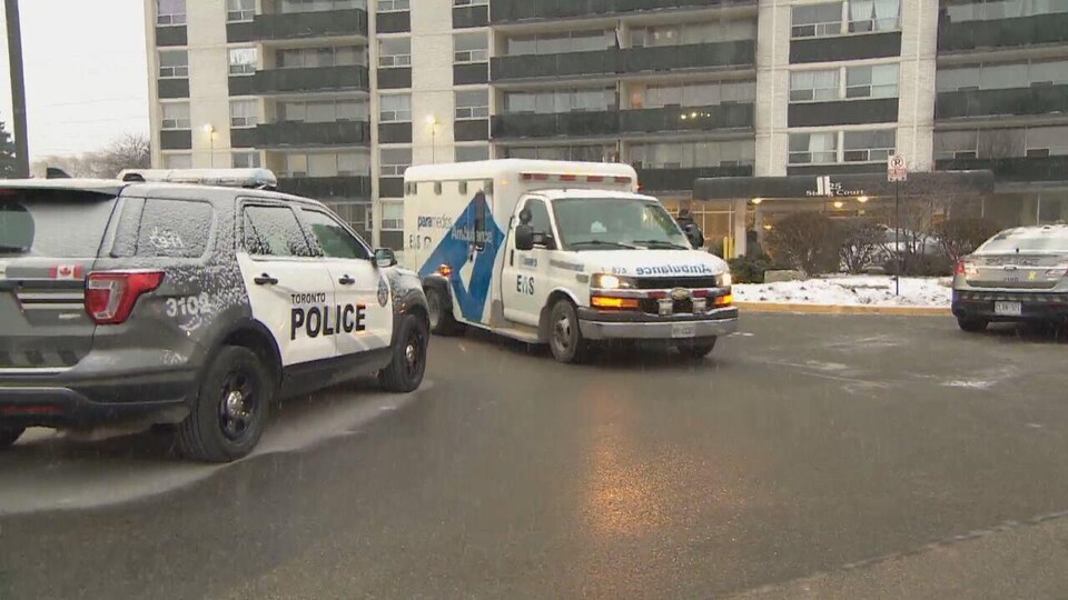 Des autopatrouilles et une ambulance devant l'immeuble d'appartements où la fusillade a eu lieu.