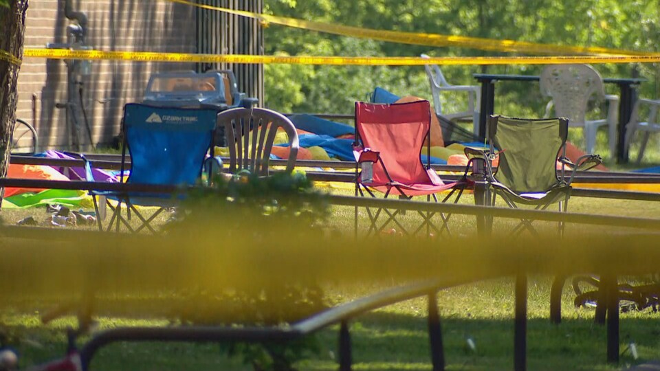 Des chaises dans un parc à l'extérieur avec le ruban jaune de la police qui indique une scène de crime.
