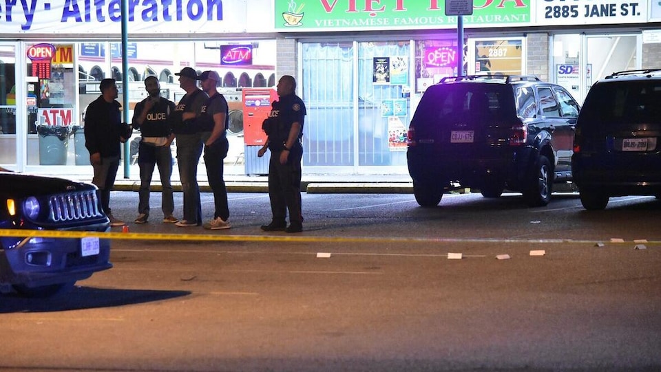 Des policiers se tiennent sur les lieux de la fusillade devant des magasins. 