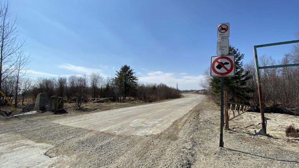 Une affiche à l'entrée d'un chemin de gravier.