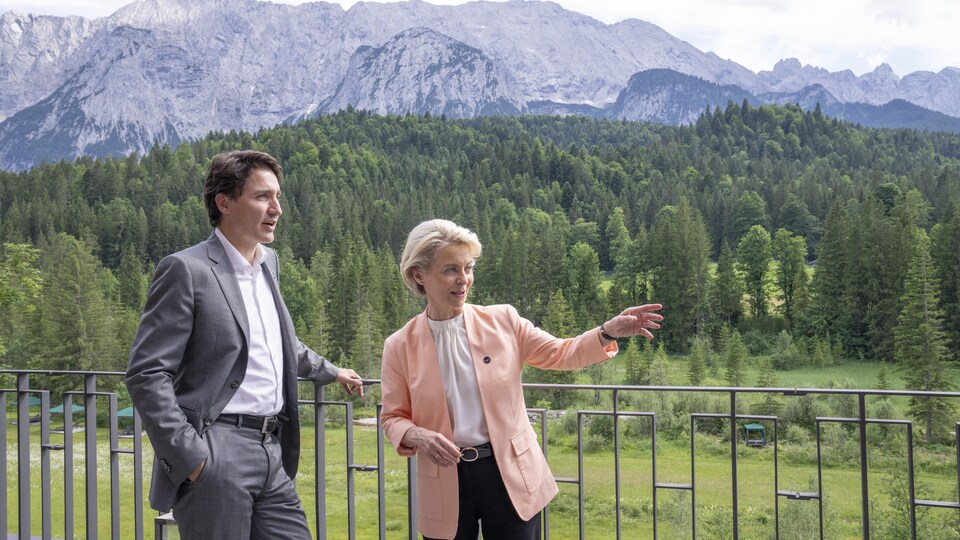 Justin Trudeau (à gauche) et Ursula von der Leyen (à droite) sur une terrasse devant un paysage montagneux forestier.