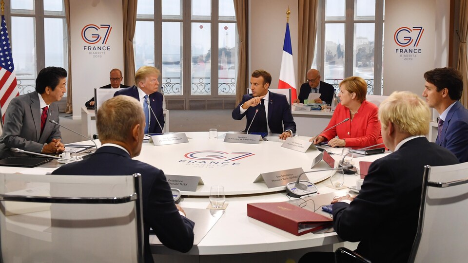 Sept dirigeants assis autour d'une table ronde.
