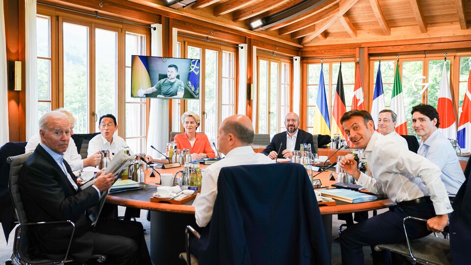 Les dirigeants des pays du G7 et de l'UE sont assis autour d'une table ronde. Le président Zelensky est visible sur un écran de télévision.