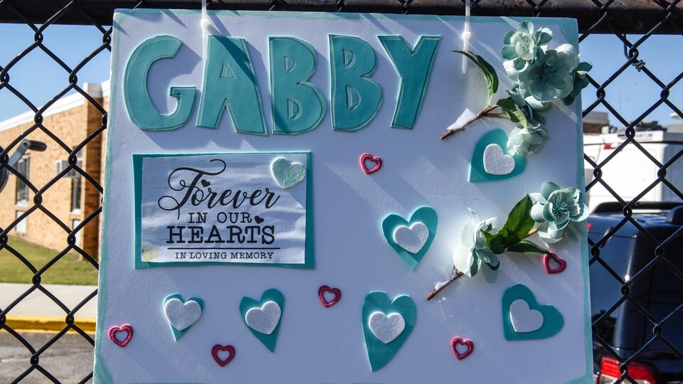 Une pancarte artisanale avec des coeurs et des fleurs sur laquelle il est écrit en anglais : « Gabby, à jamais dans nos coeurs ».