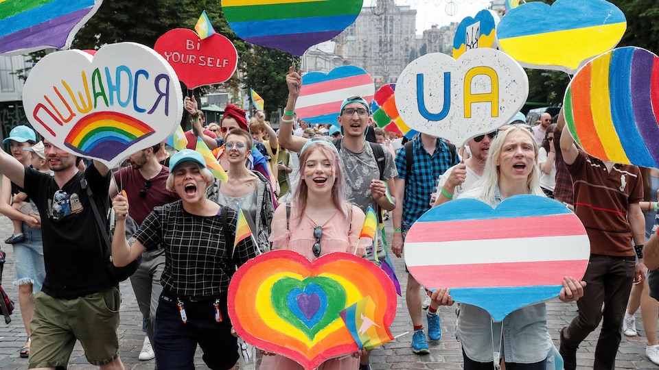 Des hommes et des femmes brandissent des pancartes multicolores en forme de cœur dans une rue de Kiev, en Ukraine.