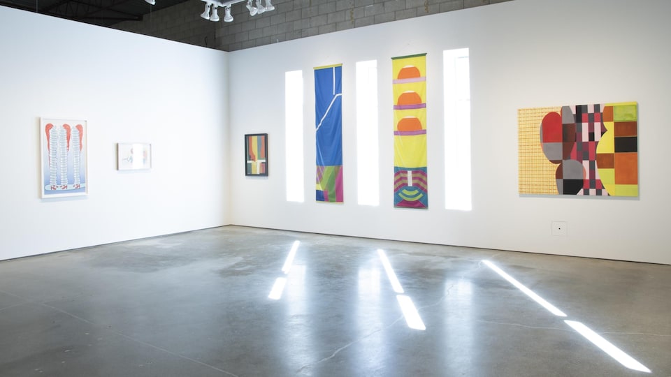 Des peintures d'art contemporain sur un mur blanc.