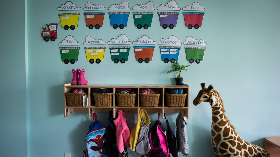 L'entrée d'une garderie, avec des casiers, des sacs à dos et une girafe en peluche.