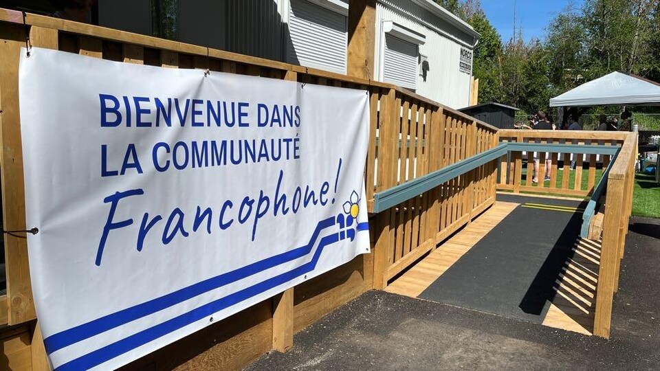 Une banderole accrochée sur une structure en bois souhaite la bienvenue dans la communauté francophone.