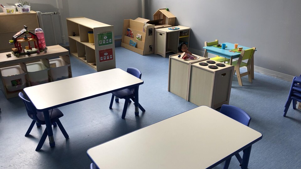 Une salle de garderie vide avec des tables et des jeux.