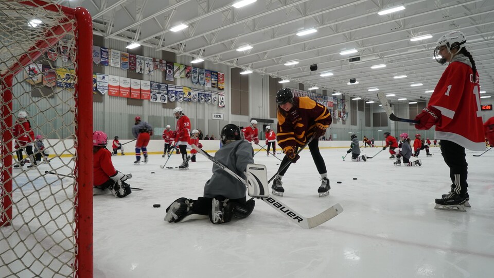 Une joueuse de hockey devant une jeune gardienne de but sur la patinoire.