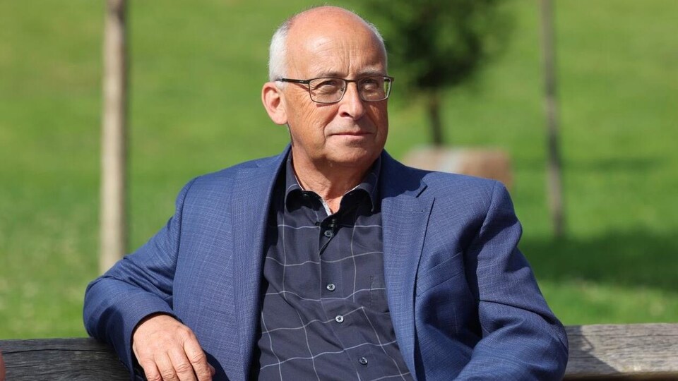 Gary Burrill, assis sur un banc dans un parc.