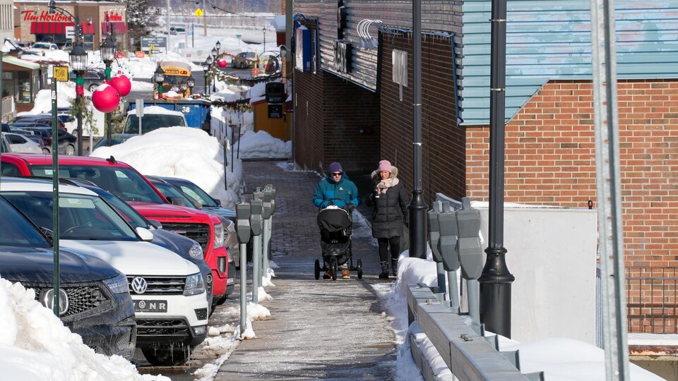 Deux personnes marchent sur le côté de la rue en hiver.