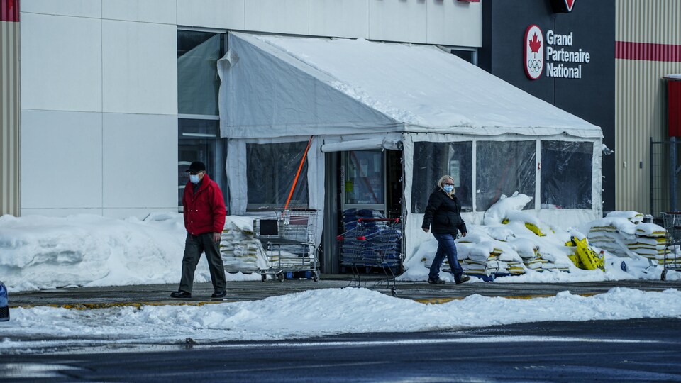 Deux personnes sortent d'un magasin à Gaspé en hiver.
