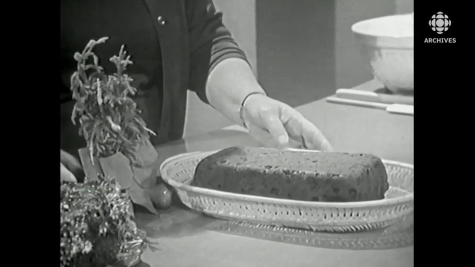 Un gâteau aux fruits est posé dans une corbeille, près de décorations de Noël.