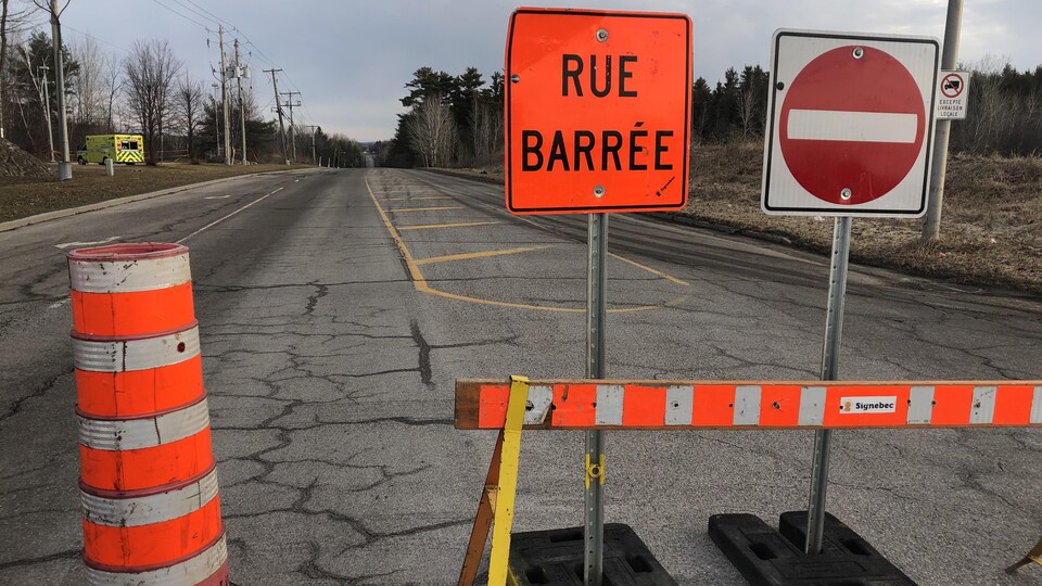 Un cône et des affiches pour signaler une rue fermée.