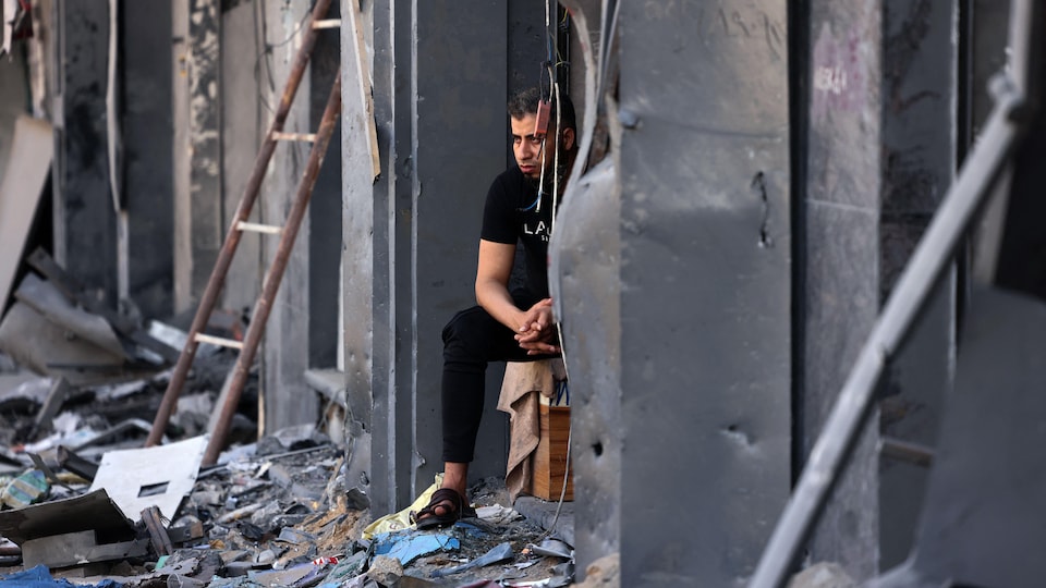 Un homme assis au milieu des ruines de son magasin à Gaza.