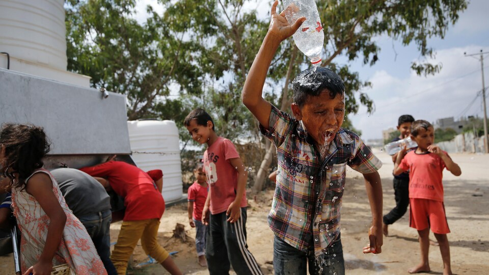 Un enfant verse de l'eau sur sa tête.