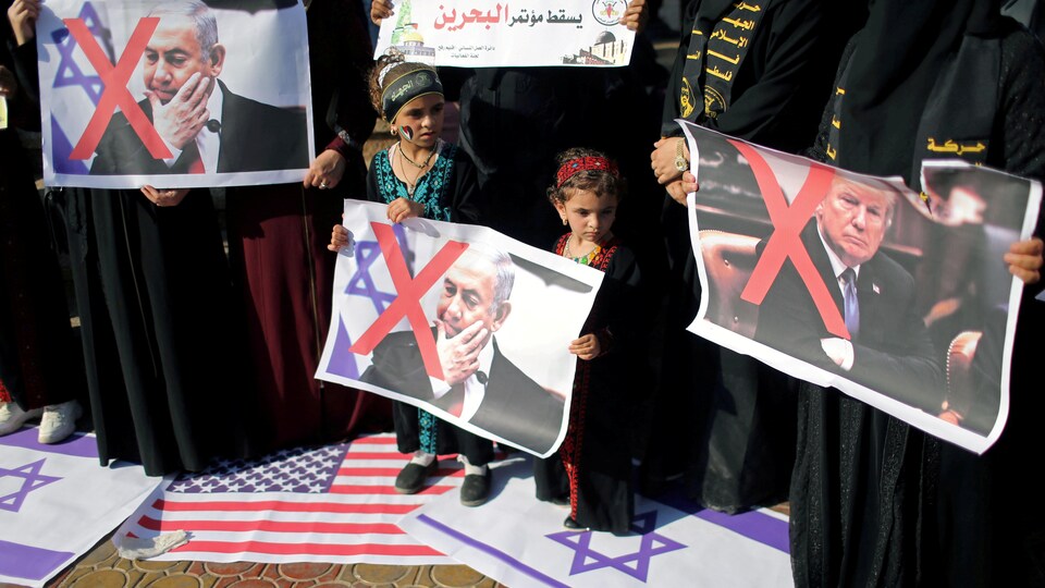 Des enfants tiennent une photo sur laquelle un X rouge est tracé sur le premier ministre israélien Benyamin Nétanyahou. Une autre photo du président américain Donald Trump est aussi marquée d'un X rouge.
