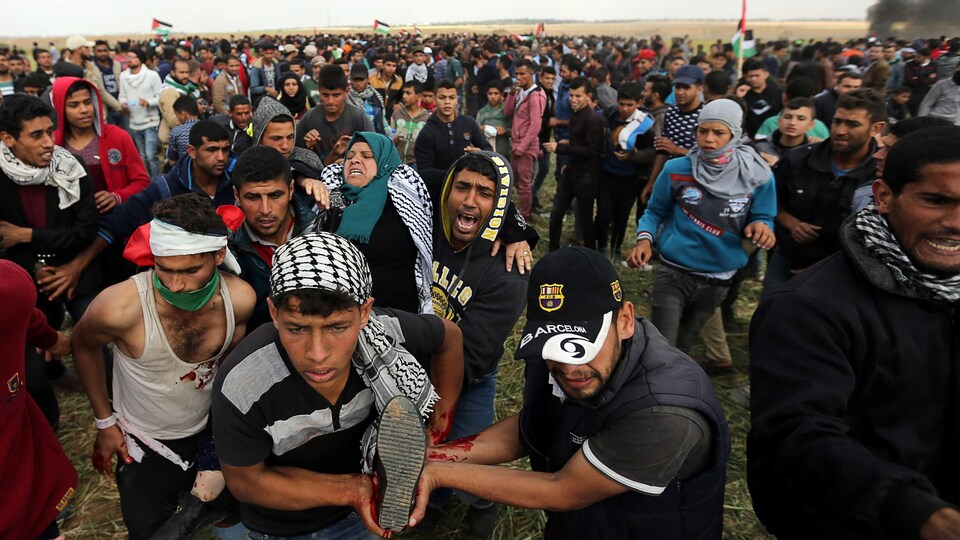 Une Palestinienne blessée est emportée par un groupe d'hommes à travers la foule.