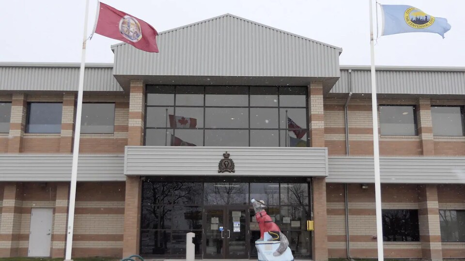Un bâtiment de la Gendarmerie royale du Canada avec des flocons de neige et deux drapeaux. 